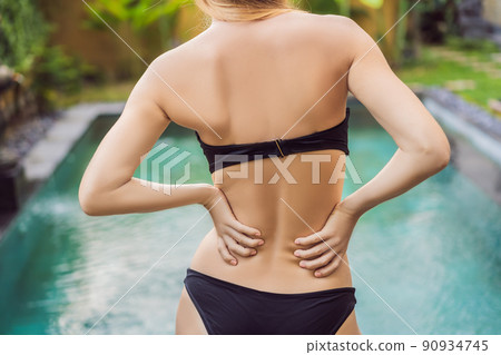 Women's back hurts against the backdrop of the pool. Pool helps with back pain Women's back hurts against the backdrop of the pool. Pool helps with back pain 90934745