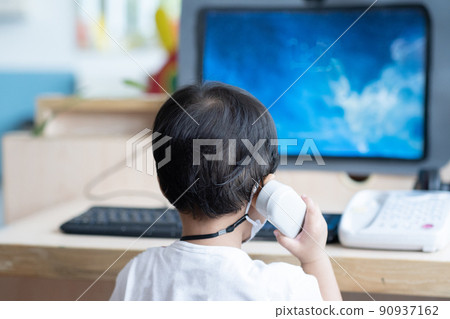 Asian Baby boy with black hair talking to telephone in front of computer laptop notebook 90937162