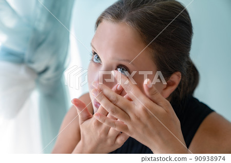 Young grl pulled back her lower eyelid and brought contact lens to her eye to put. 90938974