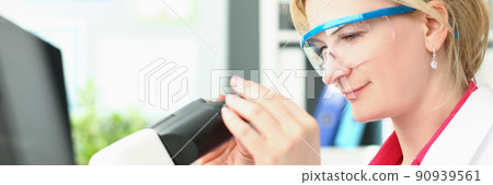 Joyful woman looks into a magnifying device, close-up Joyful woman looks into a magnifying device, close-up 90939561