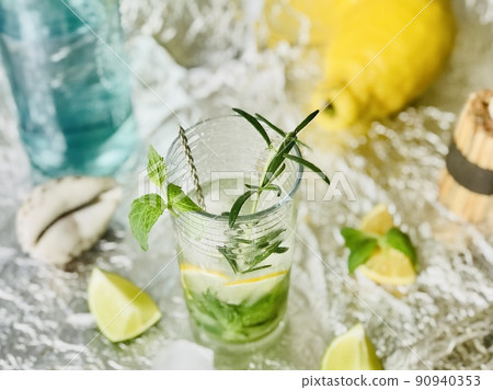 Cold lemon drink into which one can add some alcohol with ice cubes and mint on steel background with candles 90940353