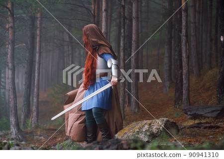 Red-haired girl in armor and raincoat in forest. Historical concept Red-haired girl in armor and raincoat in forest. Historical concept 90941310