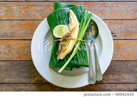 Wraped Thai food set cover by banana leaf ready to serve. Inside banana leaf is PadThai, The Traditional of Thailand Fried noodle with prawns. Wraped Thai food set cover by banana leaf ready to serve. Inside banana leaf is PadThai, The Traditional of Thailand Fried noodle with prawns. 90942930