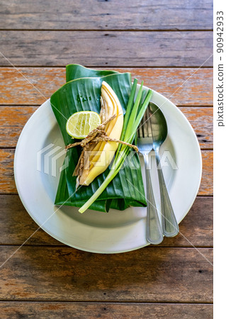 Wraped Thai food set cover by banana leaf ready to serve. Inside banana leaf is PadThai, The Traditional of Thailand Fried noodle with prawns. Wraped Thai food set cover by banana leaf ready to serve. Inside banana leaf is PadThai, The Traditional of Thailand Fried noodle with prawns. 90942933