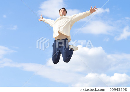 A man jumping with both hands open under the blue sky A man jumping with both hands open under the blue sky 90943398