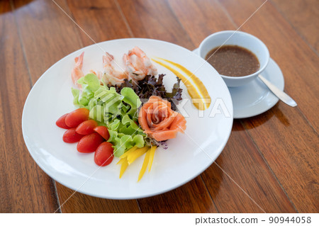 Salad raw salmon arranged to rose shape and boiled shrimp beside in the white dish on wood table. 90944058