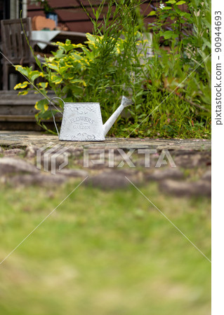 White tin watering can in the garden White tin watering can in the garden 90944693