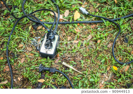 socket, plug and electric black cable on the grass in the garden. socket, plug and electric black cable on the grass in the garden. 90944913