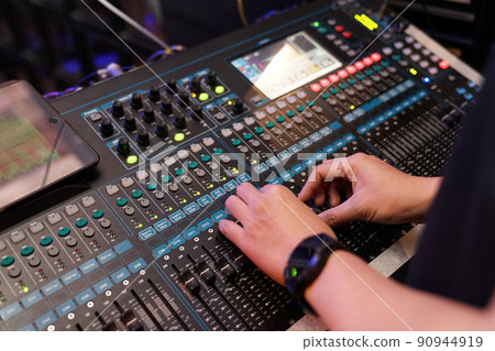 Dj controles sound controller and plays mixed edm music in the concert nightclub at a party. Dj controles sound controller and plays mixed edm music in the concert nightclub at a party. 90944919