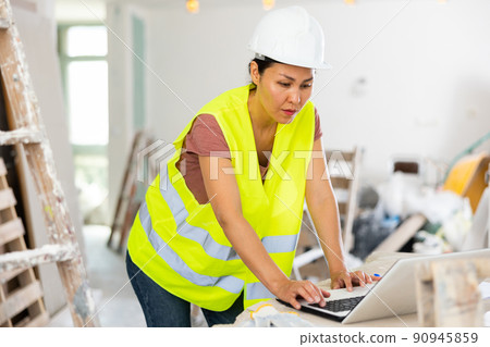 Female architect using laptop during repair works Female architect using laptop during repair works 90945859