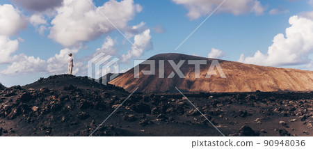 Woman rising hands up in the sky, enjoying amazing views of volcanic landscape in Timanfaya national park on Lanzarote, Spain. Freedom and travel adventure concept. Woman rising hands up in the sky, enjoying amazing views of volcanic landscape in Timanfaya national park on Lanzarote, Spain. Freedom and travel adventure concept. 90948036
