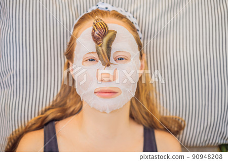Young woman makes a face mask with snail mucus. Snail crawling on a face mask 90948208