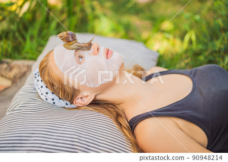 Young woman makes a face mask with snail mucus. Snail crawling on a face mask 90948214