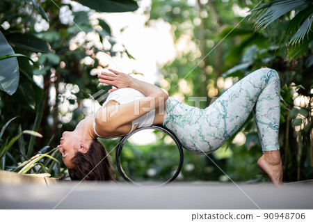 Female meditating and practicing yoga in tropical rainforest. Beautiful young woman practicing yoga outdoor with tropical forest in background. 90948706