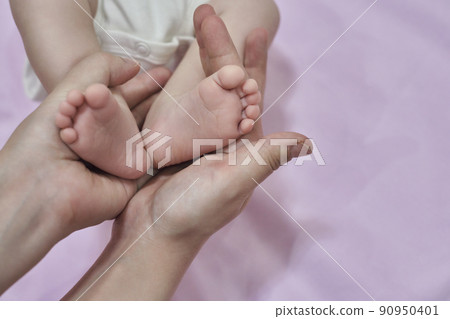 Baby feet. The mother holds with tenderness and love in his hands the small legs of a newborn. New life, parental protection, care, love, child and baby health Baby feet. The mother holds with tenderness and love in his hands the small legs of a newborn. New life, parental protection, care, love, child and baby health 90950401