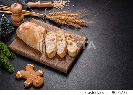French baguette bread sliced on a wooden cutting board against a dark concrete background French baguette bread sliced on a wooden cutting board against a dark concrete background 90952834