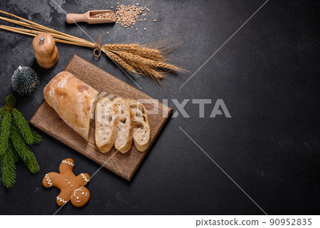French baguette bread sliced on a wooden cutting board against a dark concrete background French baguette bread sliced on a wooden cutting board against a dark concrete background 90952835