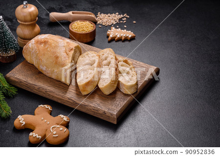 French baguette bread sliced on a wooden cutting board against a dark concrete background French baguette bread sliced on a wooden cutting board against a dark concrete background 90952836