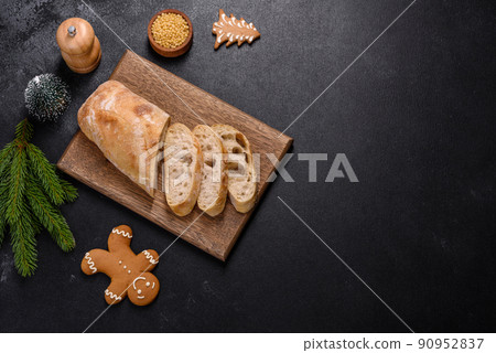 French baguette bread sliced on a wooden cutting board against a dark concrete background French baguette bread sliced on a wooden cutting board against a dark concrete background 90952837
