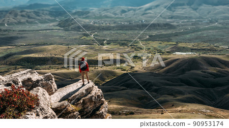 A traveler on the background of mountains. A tourist stands on top of a mountain. Male traveller in the mountains, rear view. Domestic tourism. Copy space A traveler on the background of mountains. A tourist stands on top of a mountain. Male traveller in the mountains, rear view. Domestic tourism. Copy space 90953174