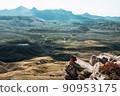 A male tourist is resting after a hard climb up the mountain, panorama. A traveler among the Rocky Mountains. A man is a traveler with a backpack among the rocks. Backpacking in the mountains 90953175