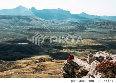 A male tourist is resting after a hard climb up the mountain, panorama. A traveler among the Rocky Mountains. A man is a traveler with a backpack among the rocks. Backpacking in the mountains A male tourist is resting after a hard climb up the mountain, panorama. A traveler among the Rocky Mountains. A man is a traveler with a backpack among the rocks. Backpacking in the mountains 90953175