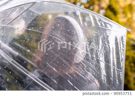 Autumn. Lonely sad woman in a headphones walking in a park, garden. View through wet transparent umbrella with rain drops. Rainy day landscape. Vintage Toned Autumn. Lonely sad woman in a headphones walking in a park, garden. View through wet transparent umbrella with rain drops. Rainy day landscape. Vintage Toned 90953751