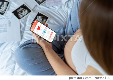 Pregnancy app. Mobile pregnancy online maternity application. Pregnant mother using phone. Pregnancy, medicine, pharmaceutics, health care and people concept. 90954100