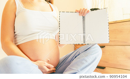 Childbirth checklist pregnant woman. Beautiful pregnancy woman writing check list. Happy pregnant lady holding notepad. Concept of maternity, expectation. 90954104