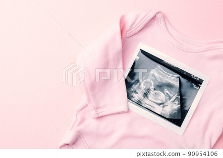 Ultrasound photo pregnancy baby. Fashion cute baby cloth with ultrasound pregnancy picture on pink background. Concept of pregnancy, maternity, expectation for baby birth. Ultrasound photo pregnancy baby. Fashion cute baby cloth with ultrasound pregnancy picture on pink background. Concept of pregnancy, maternity, expectation for baby birth. 90954106