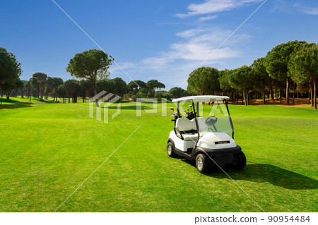Golf cart on a golf course with green grass field with blue sky and trees in Belek, Turkey 90954484