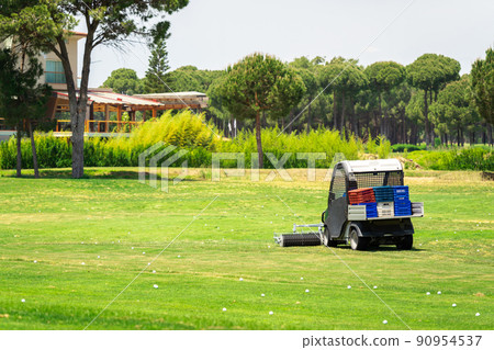 Golf course and golf cart collecting golf balls. Ballpicker on driving range of golf club 90954537