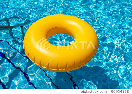 Yellow ring floating in refreshing blue swimming pool Yellow ring floating in refreshing blue swimming pool 90954558