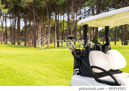 Set of golf clubs in golf bags in the back of a golf cart on a beautiful golf course Set of golf clubs in golf bags in the back of a golf cart on a beautiful golf course 90954563
