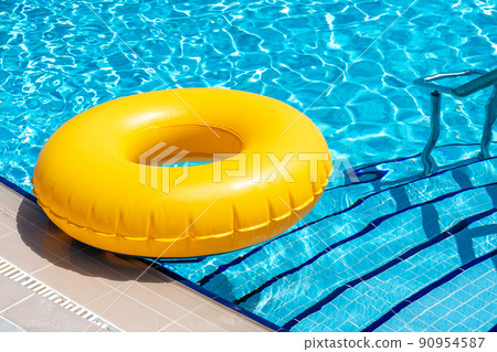 Yellow ring floating in blue swimming pool. Inflatable ring, rest concept Yellow ring floating in blue swimming pool. Inflatable ring, rest concept 90954587
