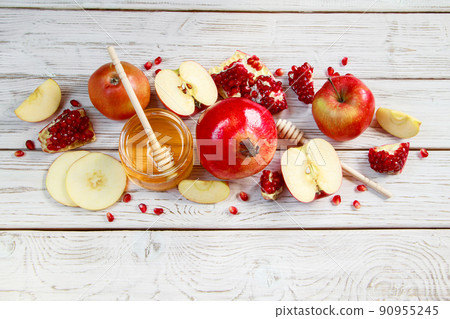 Jar with honey, apples and pomegranates on a white wooden background. Happy Rosh Hashanah. Traditional symbols of the Jewish New Year celebration. Jar with honey, apples and pomegranates on a white wooden background. Happy Rosh Hashanah. Traditional symbols of the Jewish New Year celebration. 90955245