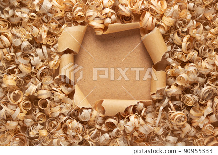 Wood shavings at torn paper background. Wooden shaving on cardboard texture Wood shavings at torn paper background. Wooden shaving on cardboard texture 90955333