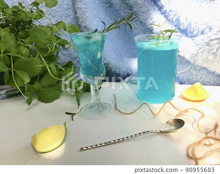 Blue cold drink in a glass with ice cubes on natural sun light. Blue cold drink in a glass with ice cubes on natural sun light. 90955683