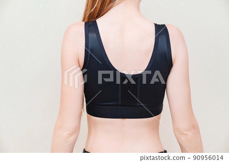 A young woman in black compression underwear after mammoplasty. 90956014