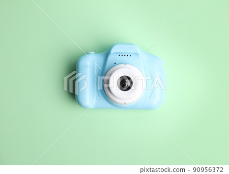Light blue toy camera on light green background, top view. Future photographer Light blue toy camera on light green background, top view. Future photographer 90956372