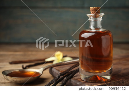 Aromatic homemade vanilla extract on wooden table, closeup. Space for text 90956412