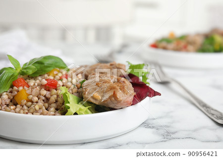 Tasty buckwheat porridge with meat on white marble table, closeup 90956421