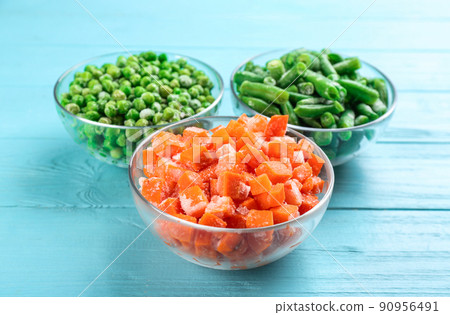 Different tasty frozen vegetables on light blue wooden table 90956491