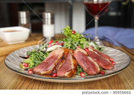 Delicious salad with roasted duck breast served on wooden table indoors 90956668