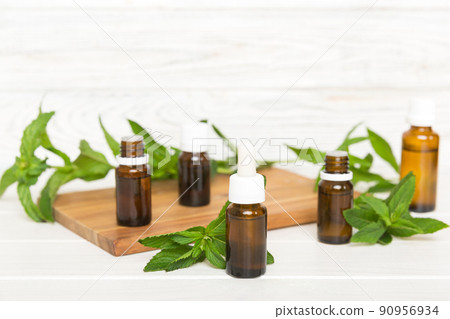 Natural Mint Essential Oil in a Glass Bottle. organic cosmetics with herbal extracts of mint on colored background 90956934