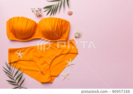 Woman swimwear and beach accessories flat lay top view on colored background Summer travel concept. bikini swimsuit, straw hat and seasheels. Copy space Top view 90957188