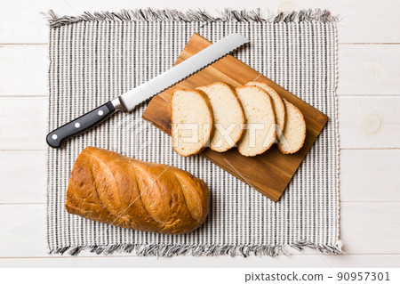 Freshly baked bread cut with knife on a wooden board. top view Sliced bread and knife 90957301