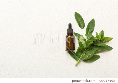 Natural Mint Essential Oil in a Glass Bottle. organic cosmetics with herbal extracts of mint on colored background 90957398