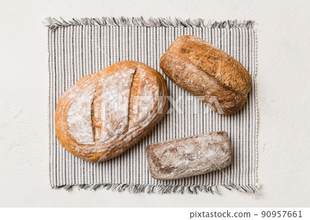 Assortment of freshly baked bread with napkin on rustic table top view. Healthy unleavened bread. French bread Assortment of freshly baked bread with napkin on rustic table top view. Healthy unleavened bread. French bread 90957661