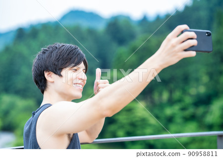 一個男人在新鮮的綠色公園背景下用智能手機自拍 一個男人在新鮮的綠色公園背景下用智能手機自拍 90958811
